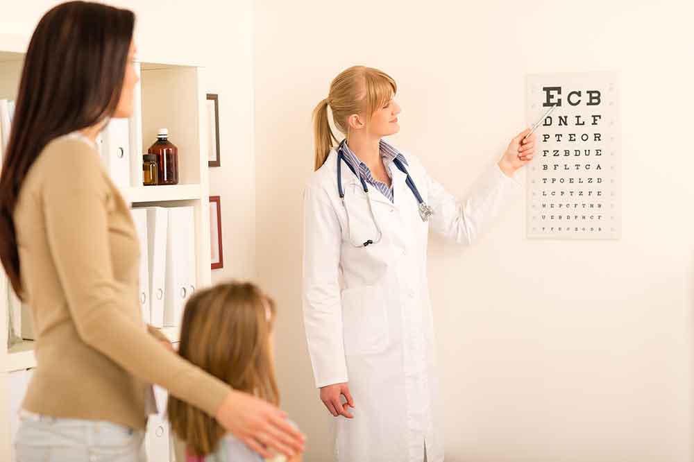 female pediatrician-pointing at eye chart for a mother and child