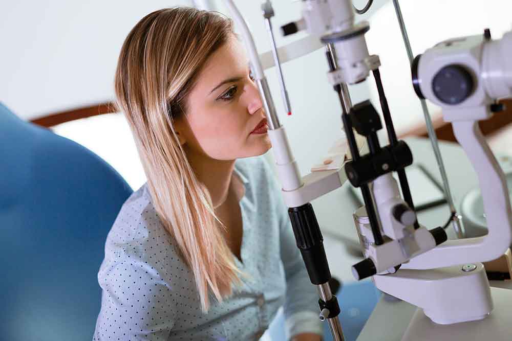 blond woman sitting in front of eye exam equipment
